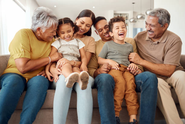 Multigenerational family with grandparents, parents, and grandchildren laughing together on a couch